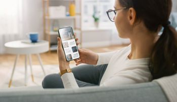 A woman sitting on her couch reading news on her phone