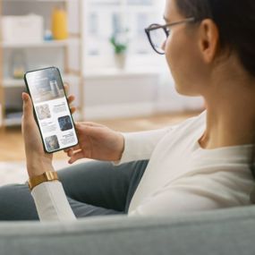 A woman sitting on her couch reading news on her phone