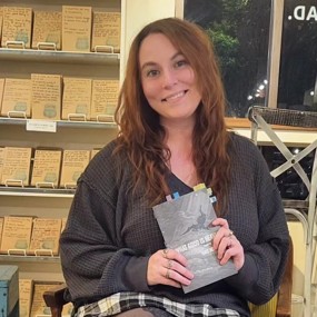Raye Hendrix holding "What Good is Heaven" at an Auburn bookstore