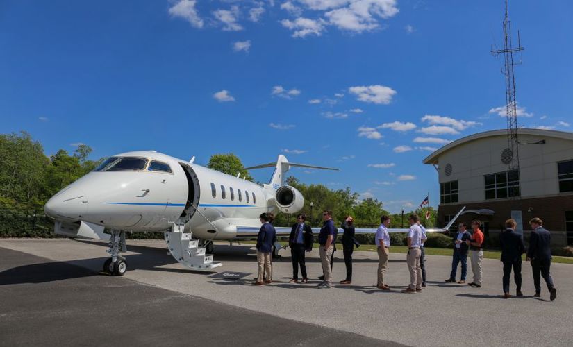 a corporate jet with a line of people waiting to take a tour of the inside of the jet