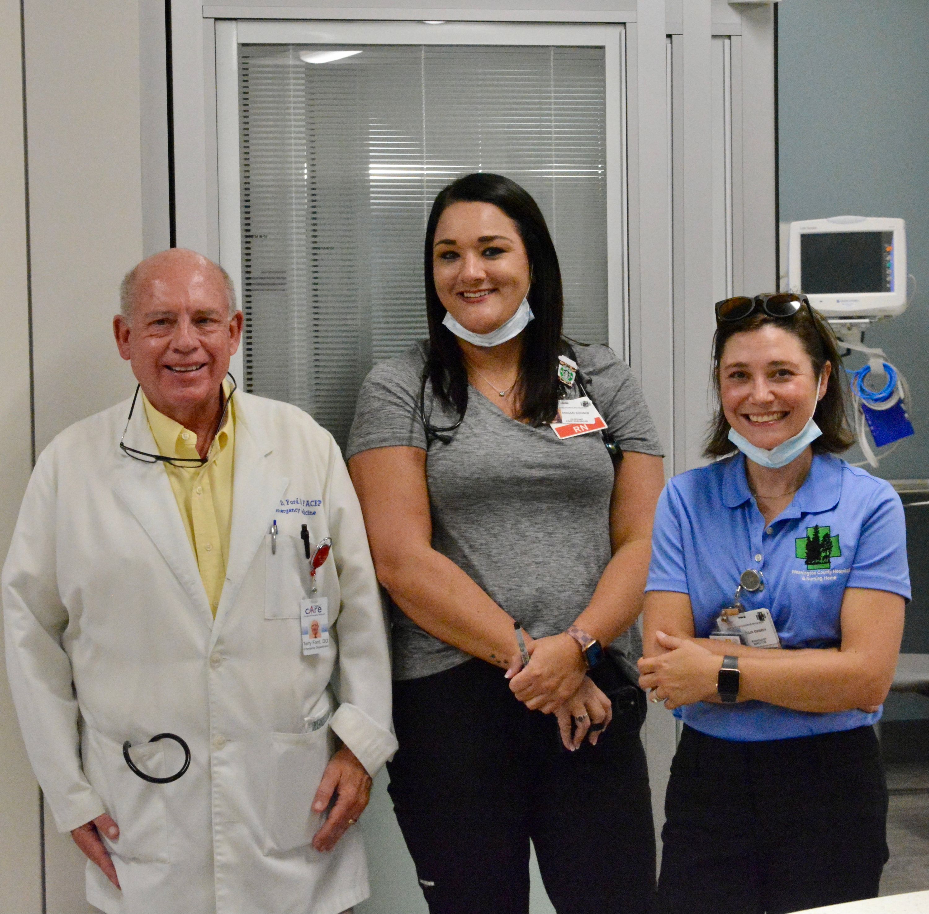 three people standing in a hospital room