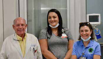 three people standing in a hospital room