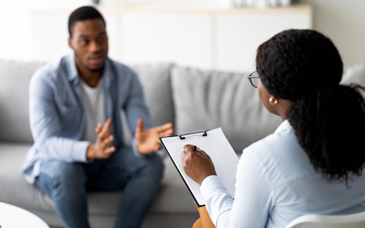 Young man with emotional problems consulting professional therapist