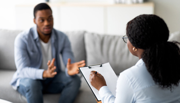 Young man with emotional problems consulting professional therapist
