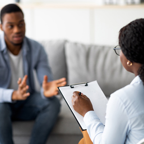 Young man with emotional problems consulting professional therapist