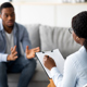 Young man with emotional problems consulting professional therapist