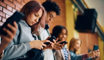 High school students using cell phones in hallway