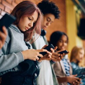 High school students using cell phones in hallway