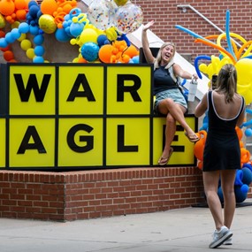 Students taking photos at a large War Eagle sign during a first week of class celebration