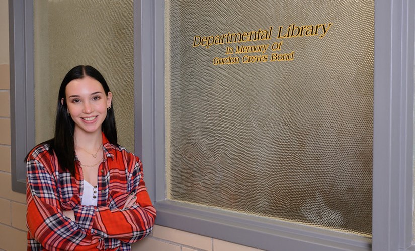 Emma Bond poses outside the Gordon Crews Bond Department of History library