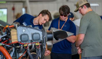 Auburn aviator pointing to parts of a plane engine