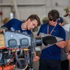 Auburn aviator pointing to parts of a plane engine