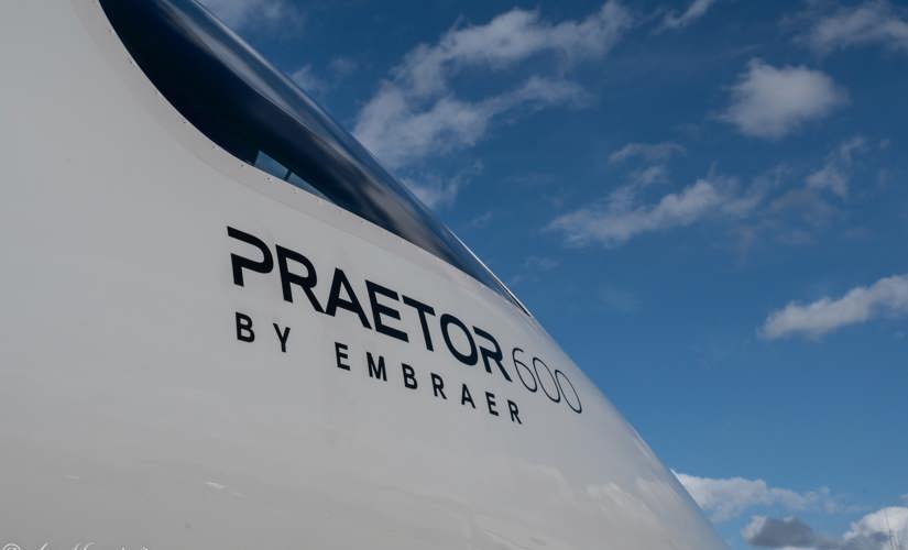 closeup shot of the words Praetor 600 by Embraer on the side of a plane 