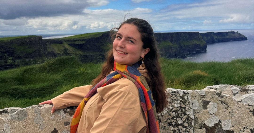Lauren Kutschke on a stone cliff during her study abroad program to Scotland