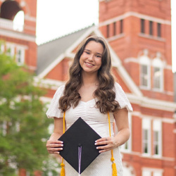 Manna stands in front of Samford Hall holding a graduation cap