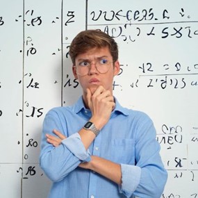 A man thinking about something in front of a classroom whiteboard