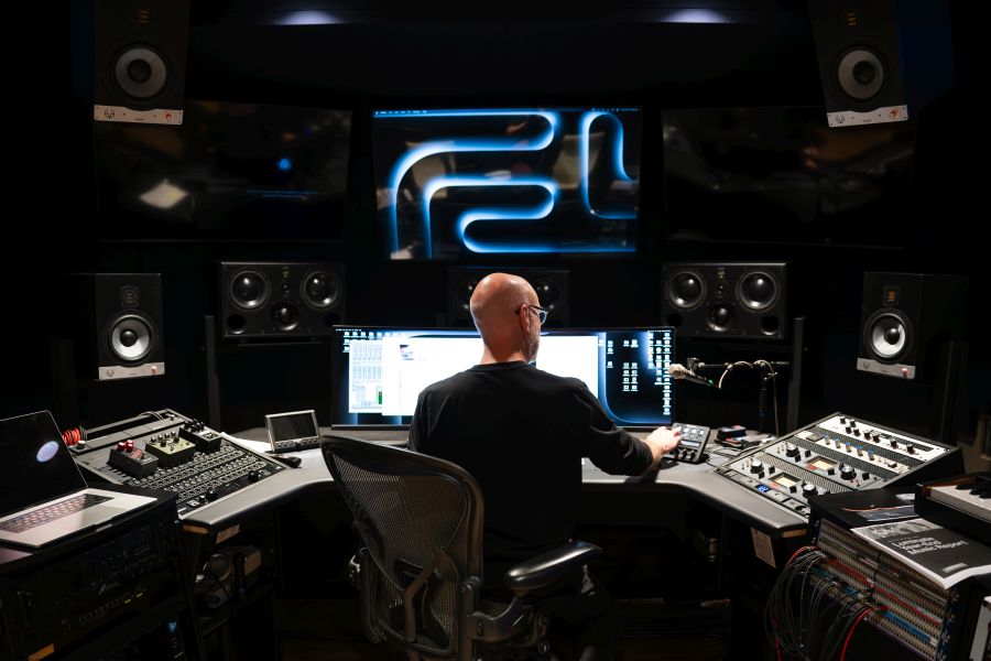 a man looking at a computer screen in a recording studio control room