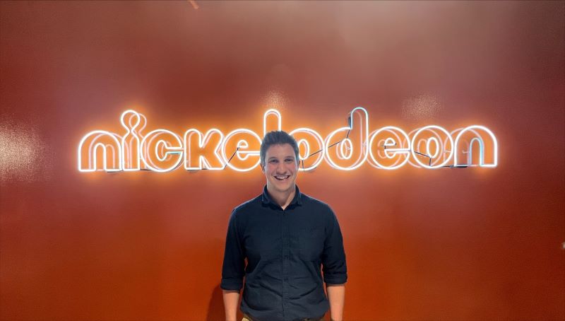 Caleb Eason stands in front of a neon NICKELODEON sign