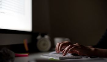 Person sits at a desk answering emails in a dark room