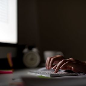 Person sits at a desk answering emails in a dark room