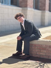 photo of man in a grey suit sitting on a concrete ledge
