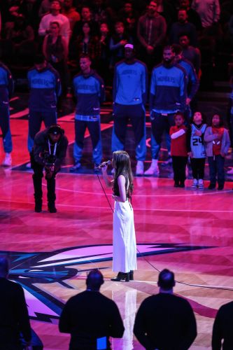 Karsen Betzold sings in front of a crowd at an NBA basketball game