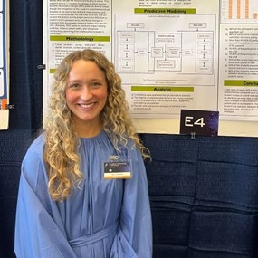 Kelly Moore stands beside her nursing students research poster presentation