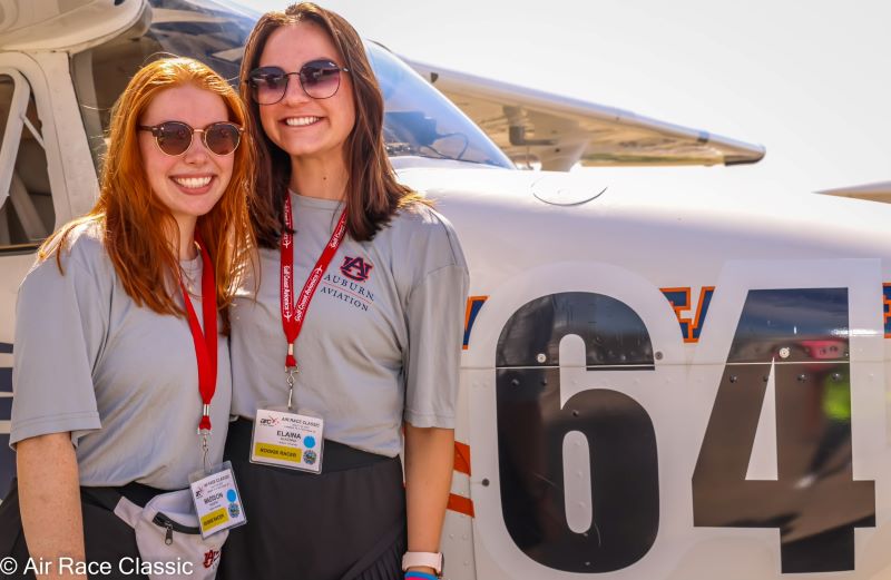 Madison Nugent and Elaina McKenna stand in front of the Team 64 Skyhawk airplane