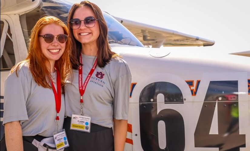 Madison Nugent and Elaina McKenna stand in front of the Team 64 Skyhawk airplane