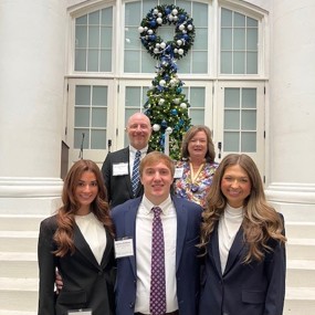 students and faculty posing for a photo in front of a large glass door