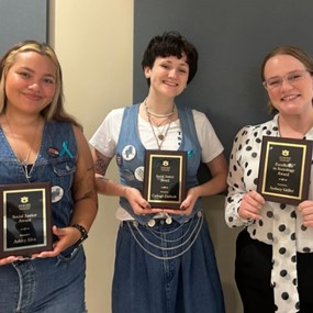 Students standing together each holding an award plaque