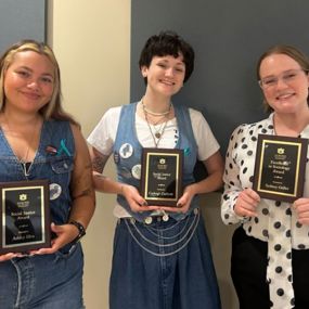 Students standing together each holding an award plaque