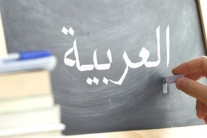 Person writing in Arabic on a chalkboard