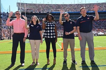 College of Liberal Arts and War Eagle Productions representatives wave on the field at Jordan Hare Stadium