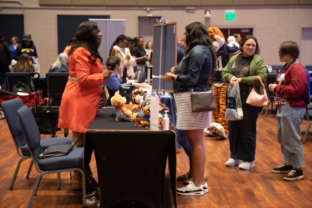 Students and parents looking at a table of promotional items and talking to a woman