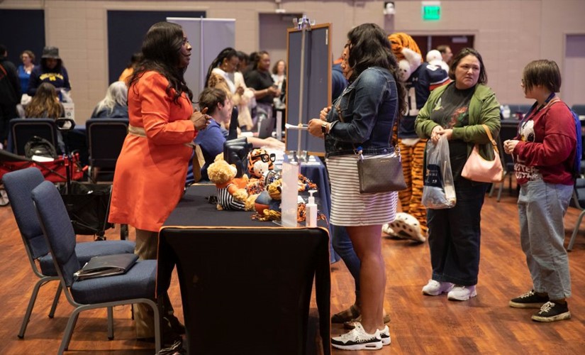 Students and parents looking at a table of promotional items and talking to a woman