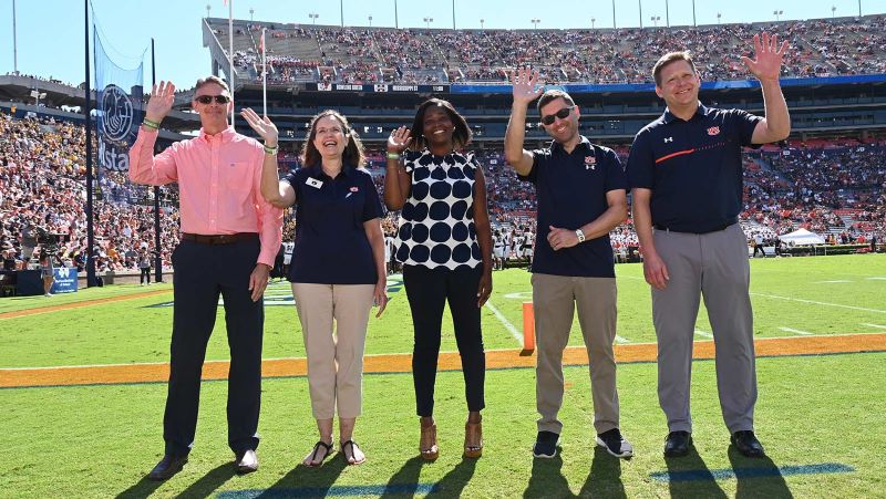 College of Liberal Arts and War Eagle Productions representatives wave on the field at Jordan Hare Stadium