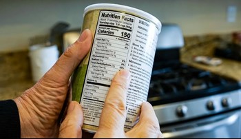Hands holding a can, pointing to Nutrition Facts label