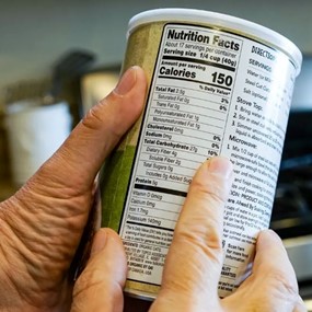 Hands holding a can, pointing to Nutrition Facts label