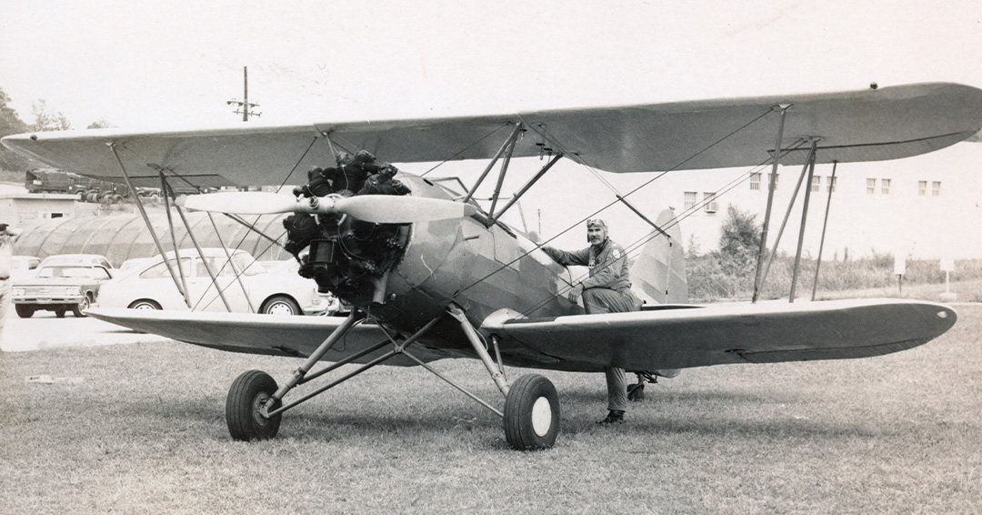 an old black and white photo of John Neher in a biplane on the ground