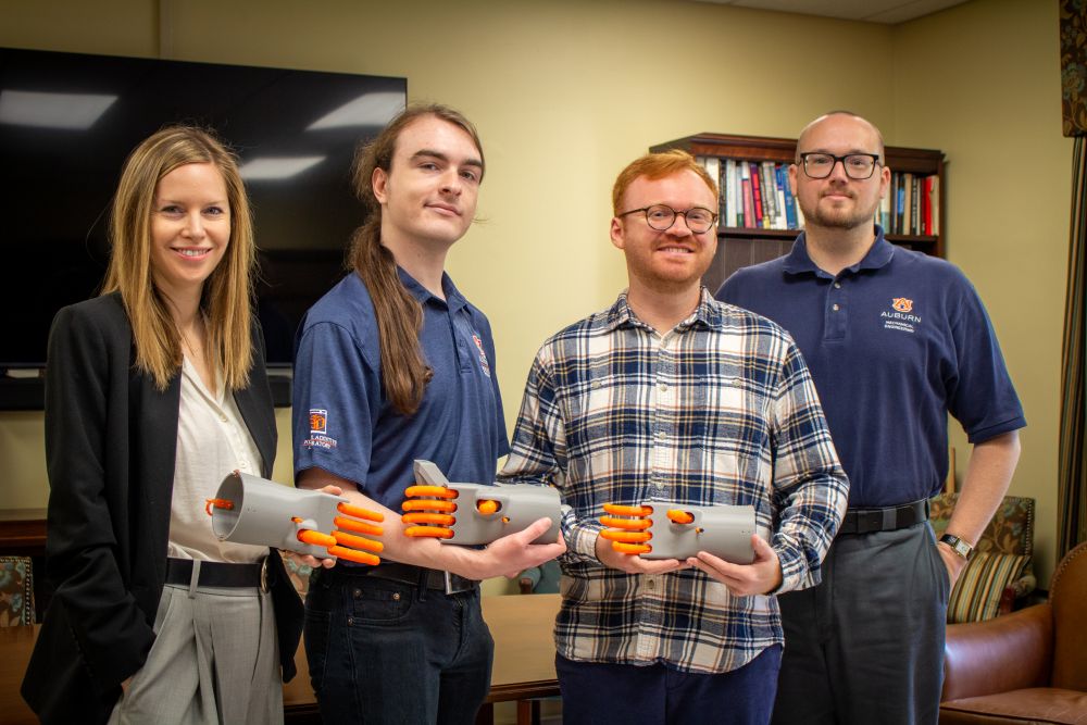 Members of the Kassel Hand research team holding 3D printed models of a mechanical hand