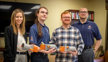 Members of the Kassel Hand research team holding 3D printed models of a mechanical hand