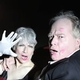 surprised man and woman in red car with policemen holding a flashlight up to their faces